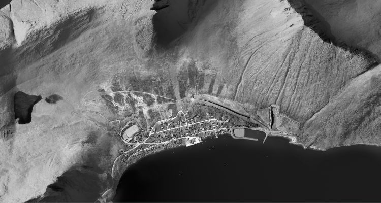 Et flyfotobilde i sort-hvitt av en liten by langs kysten 